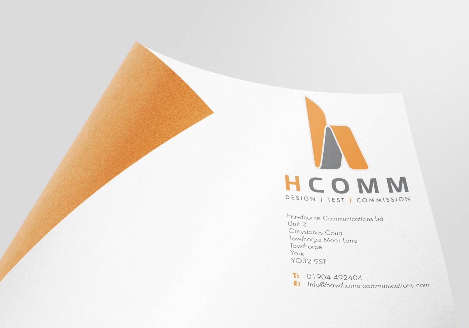 A logo close up on paper showing Hcomm Rail's logo design